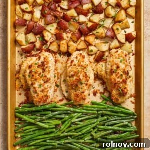 Parmesan crusted chicken sheet pan dinner cooked on baking sheet, showcasing golden-brown chicken, roasted potatoes, and green beans.