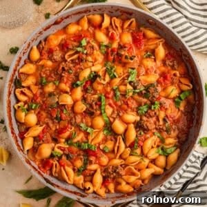 Hearty ground beef pasta in a skillet, garnished with fresh basil.