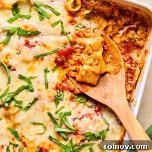 A rich Italian sausage pasta bake in a pan, with a serving spoon ready to dish out a portion.