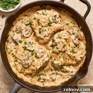 Skillet with cream of mushroom pork chops topped with fresh parsley.