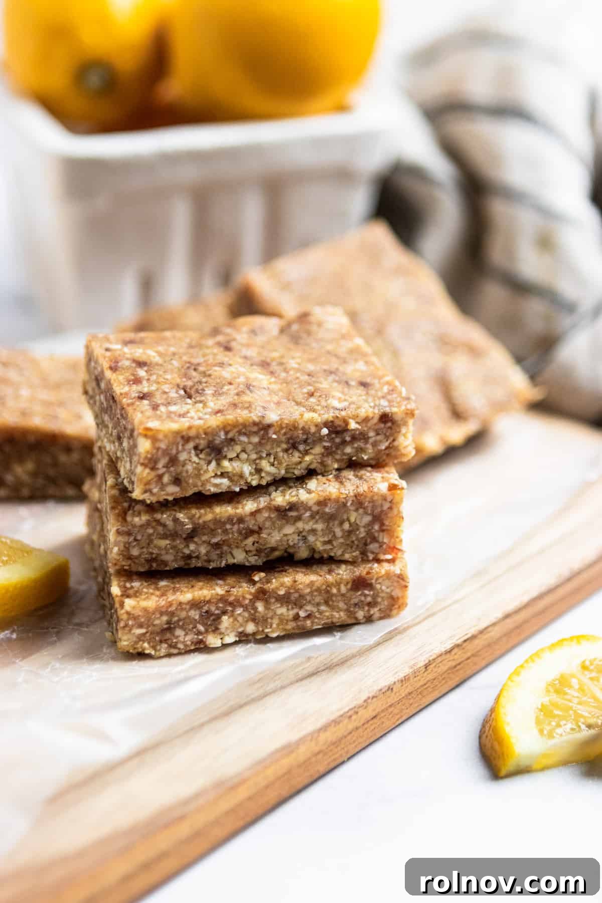 Tropical No-Bake Lemon Coconut Delights 6 Stack of lemon coconut bars on cutting board with fresh lemons.