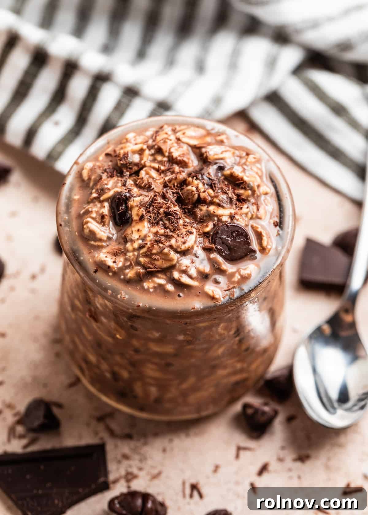 Chocolate overnight oats in glass jar topped with chocolate chips and chocolate shavings.