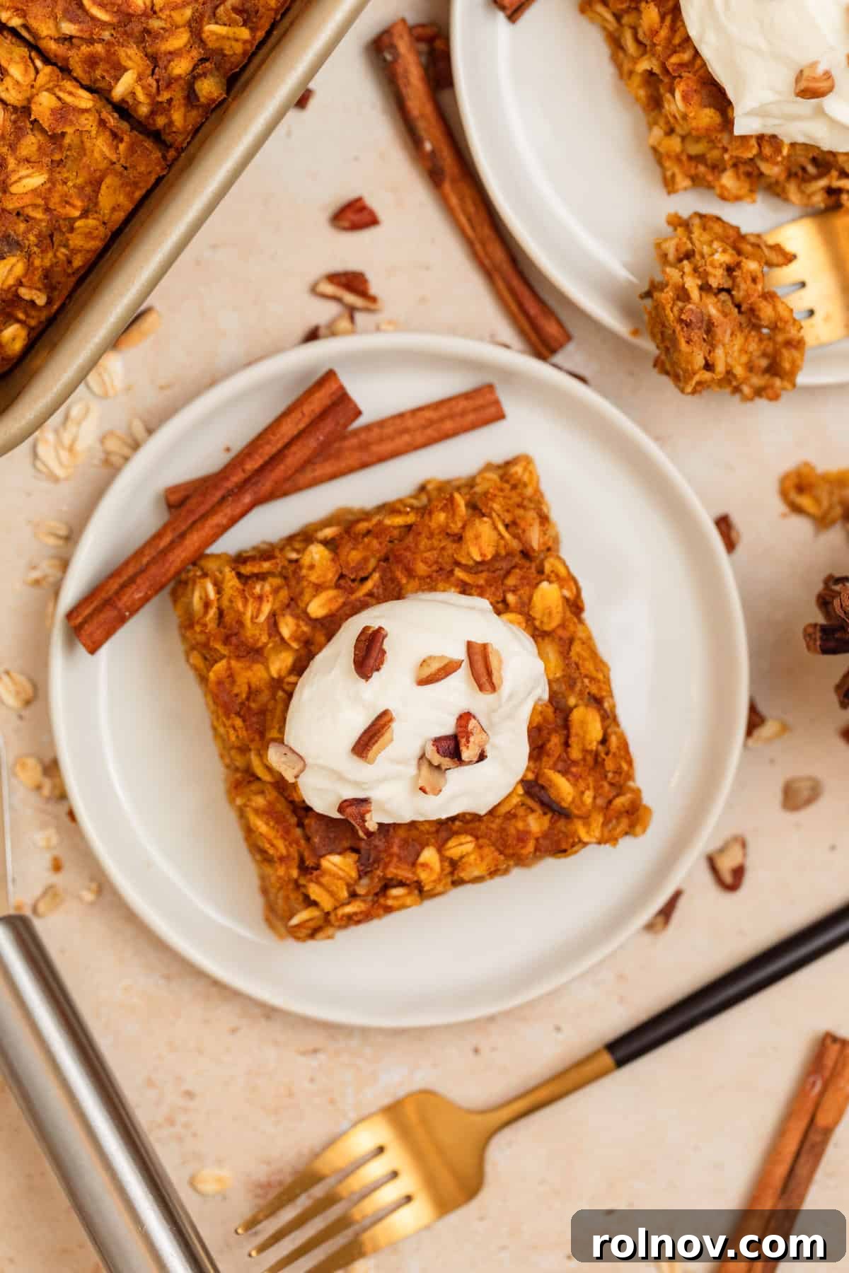 Spiced Pumpkin Oatmeal Bake 11 A white serving dish filled with warm pumpkin baked oats, beautifully presented with decorative cinnamon sticks on the side, highlighting its appeal for a fall breakfast.