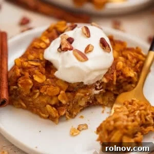 A close-up of a slice of pumpkin oatmeal bake topped with creamy yogurt and crunchy chopped pecans.