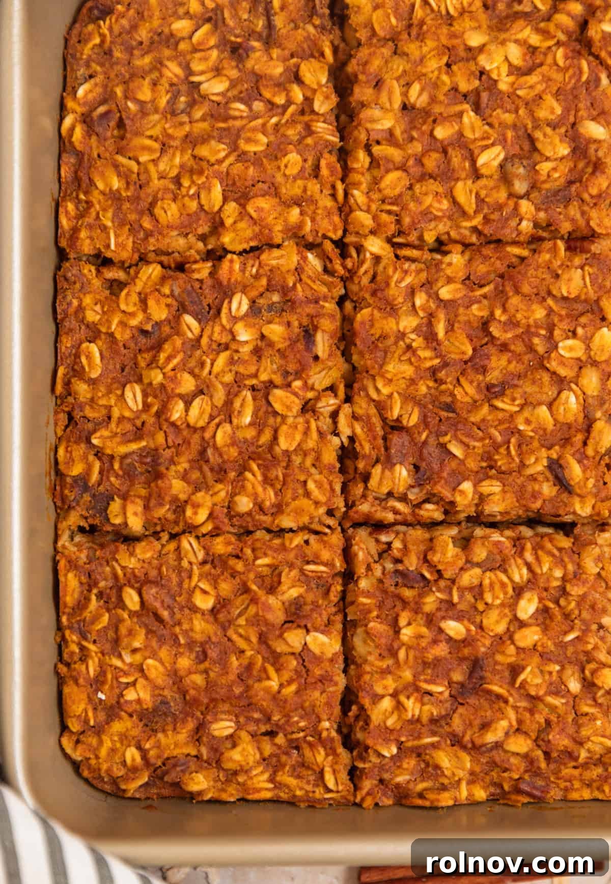 Spiced Pumpkin Oatmeal Bake 4 A freshly baked pumpkin oatmeal bake, sliced and ready to be served directly from the pan, highlighting its comforting texture and golden crust.