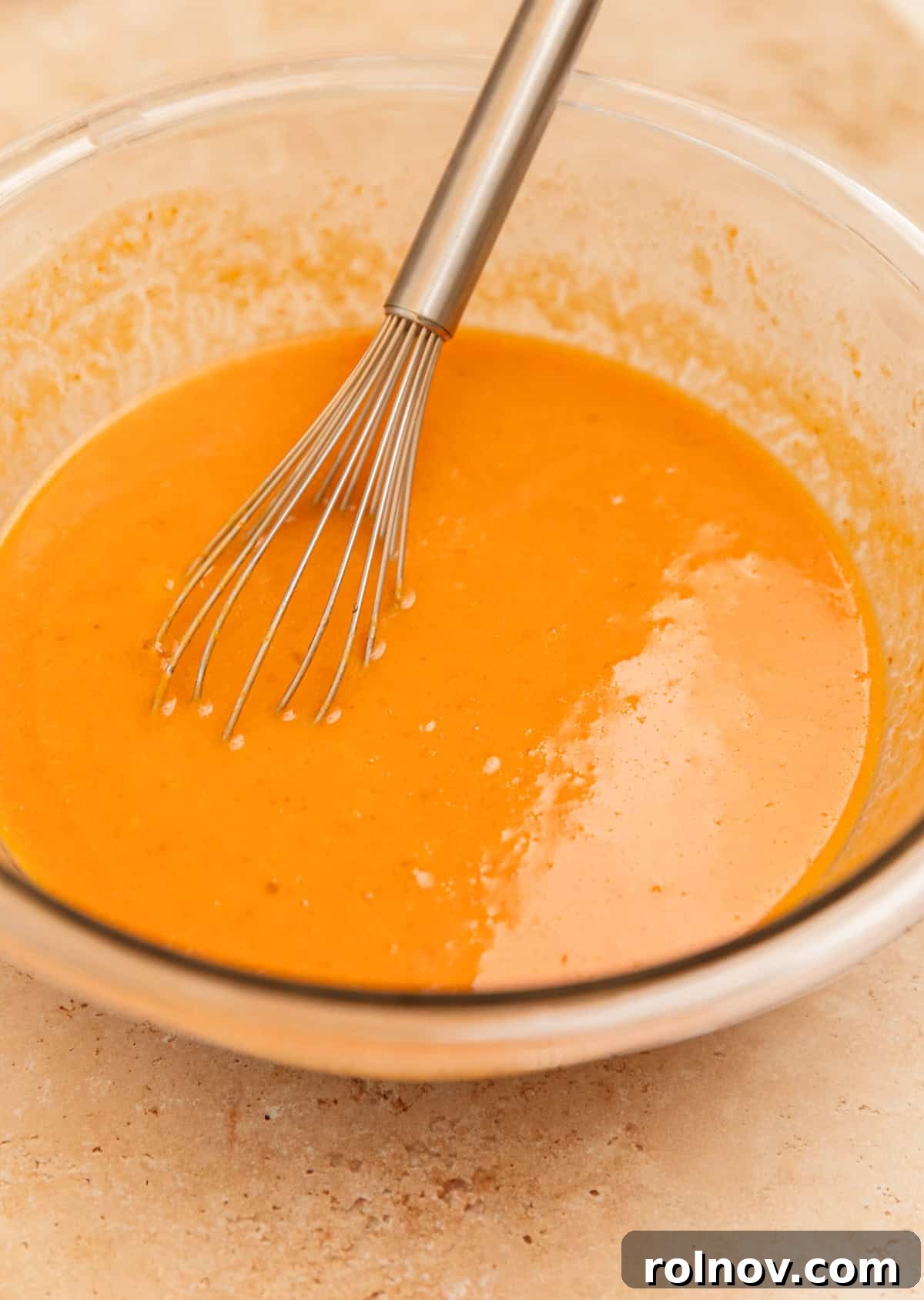 Spiced Pumpkin Oatmeal Bake 6 The pumpkin and egg mixture in a bowl, being whisked until smooth and fully incorporated, showing its vibrant orange hue.