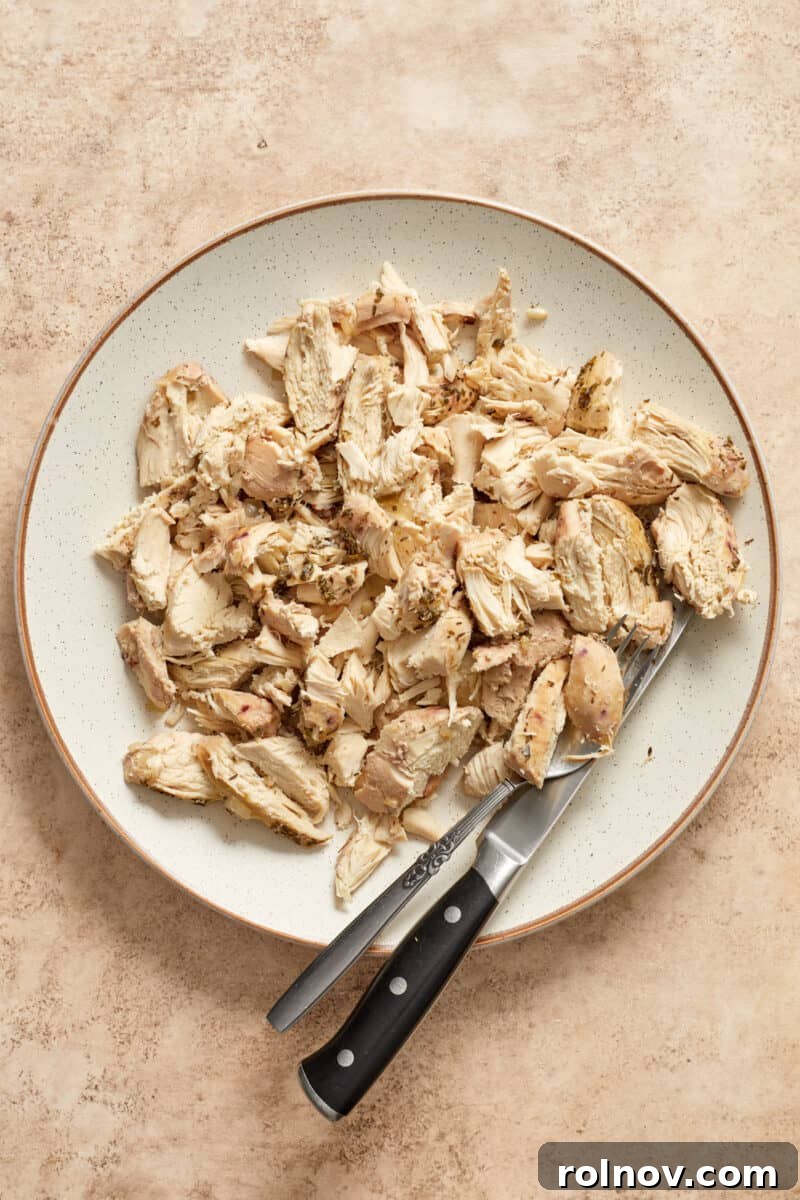 Chicken shredded on plate with fork and knife.