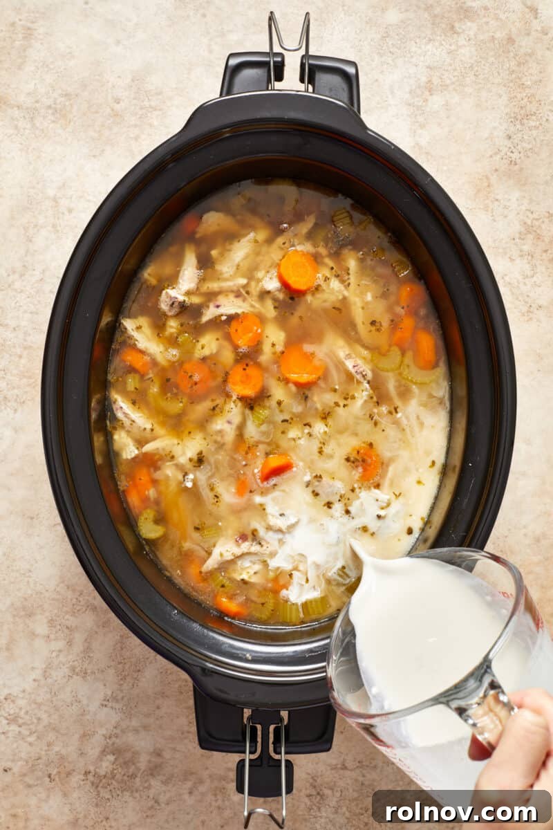 Cream being added to chicken and rice soup in crock pot.