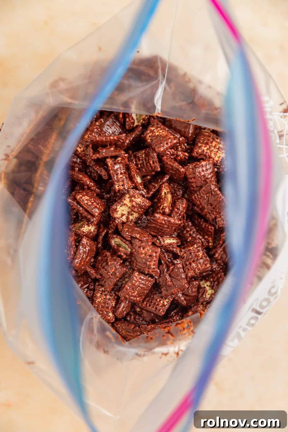 Reindeer Chow Delight 7 Powdered sugar being added to a large zip-top bag containing chocolate-coated Chex cereal.