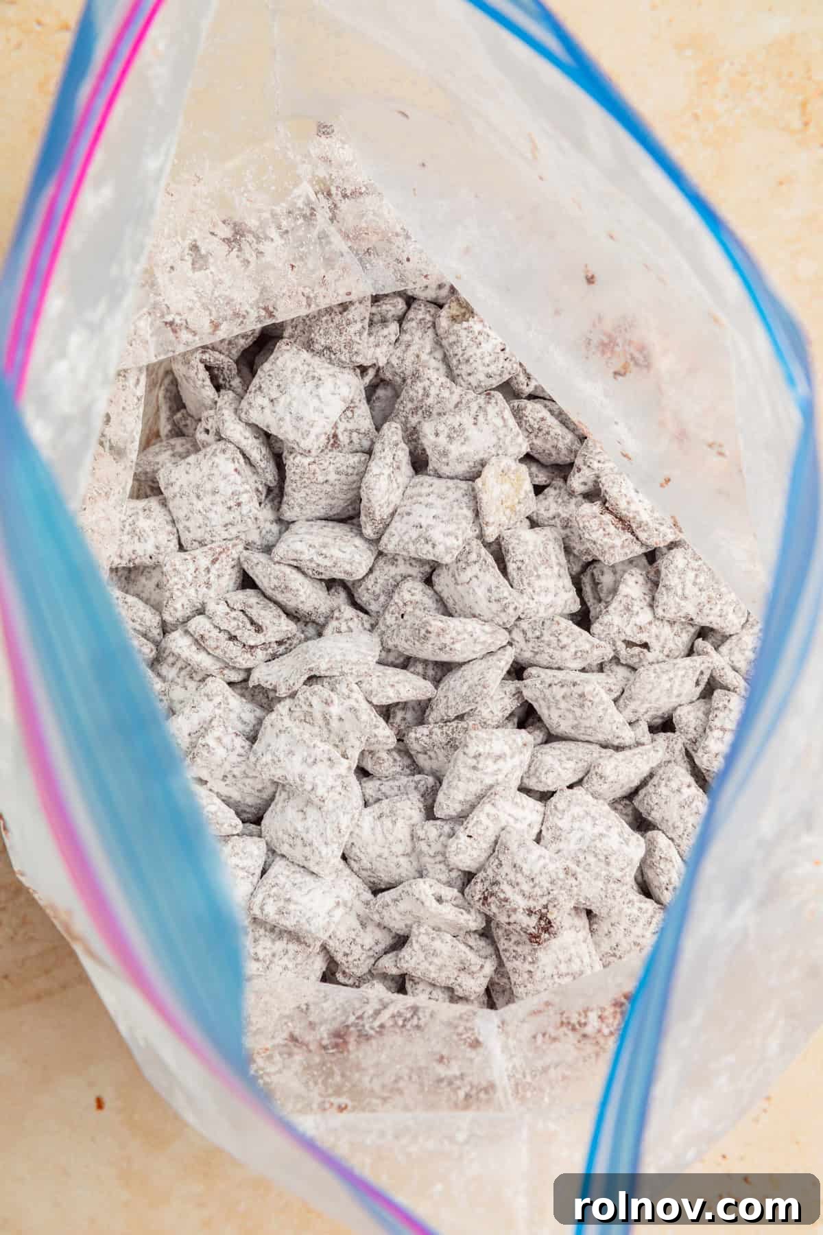 Reindeer Chow Delight 8 A close-up of powdered sugar-coated Chex cereal inside a sealed plastic bag, indicating it's ready for shaking.