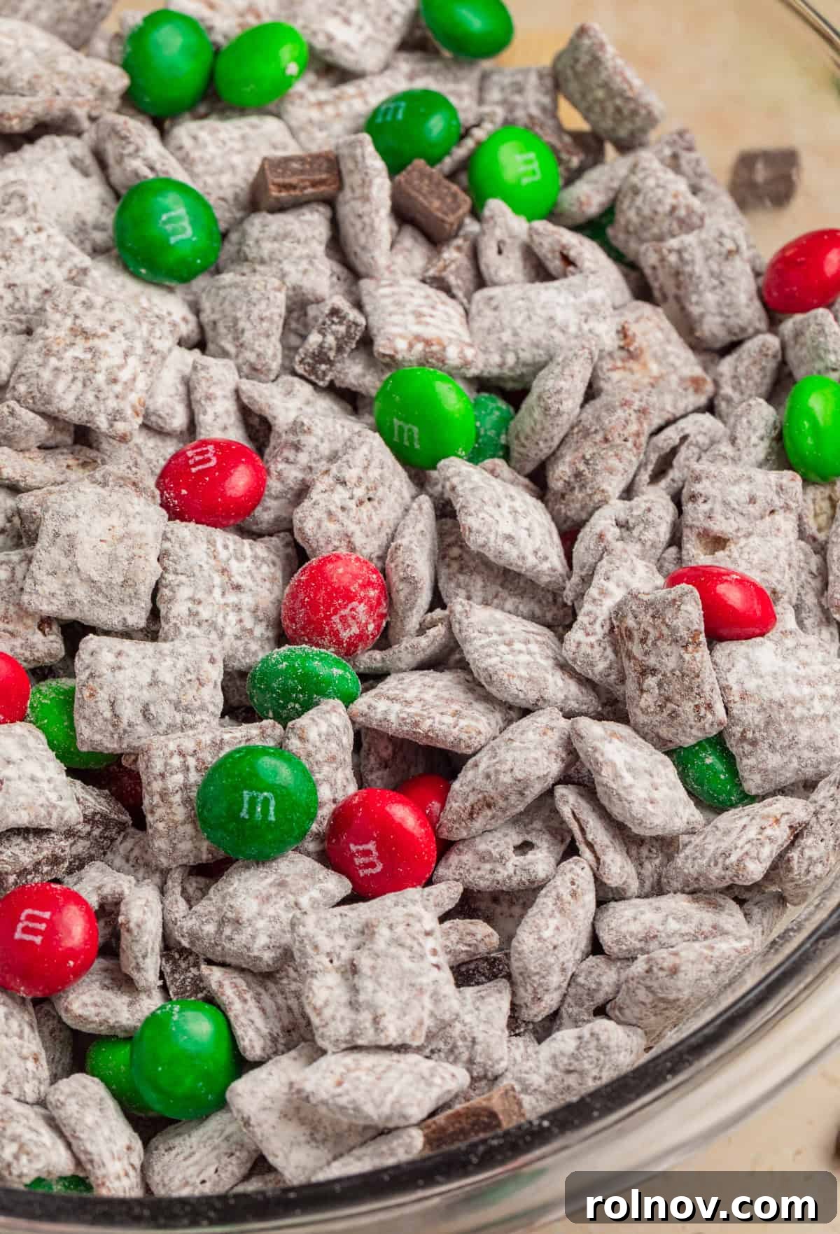 Reindeer Chow Delight 10 Close-up view of a large bowl filled with delicious Mint Chocolate Christmas Muddy Buddies, showcasing the powdered sugar, chocolate, and colorful M&Ms.