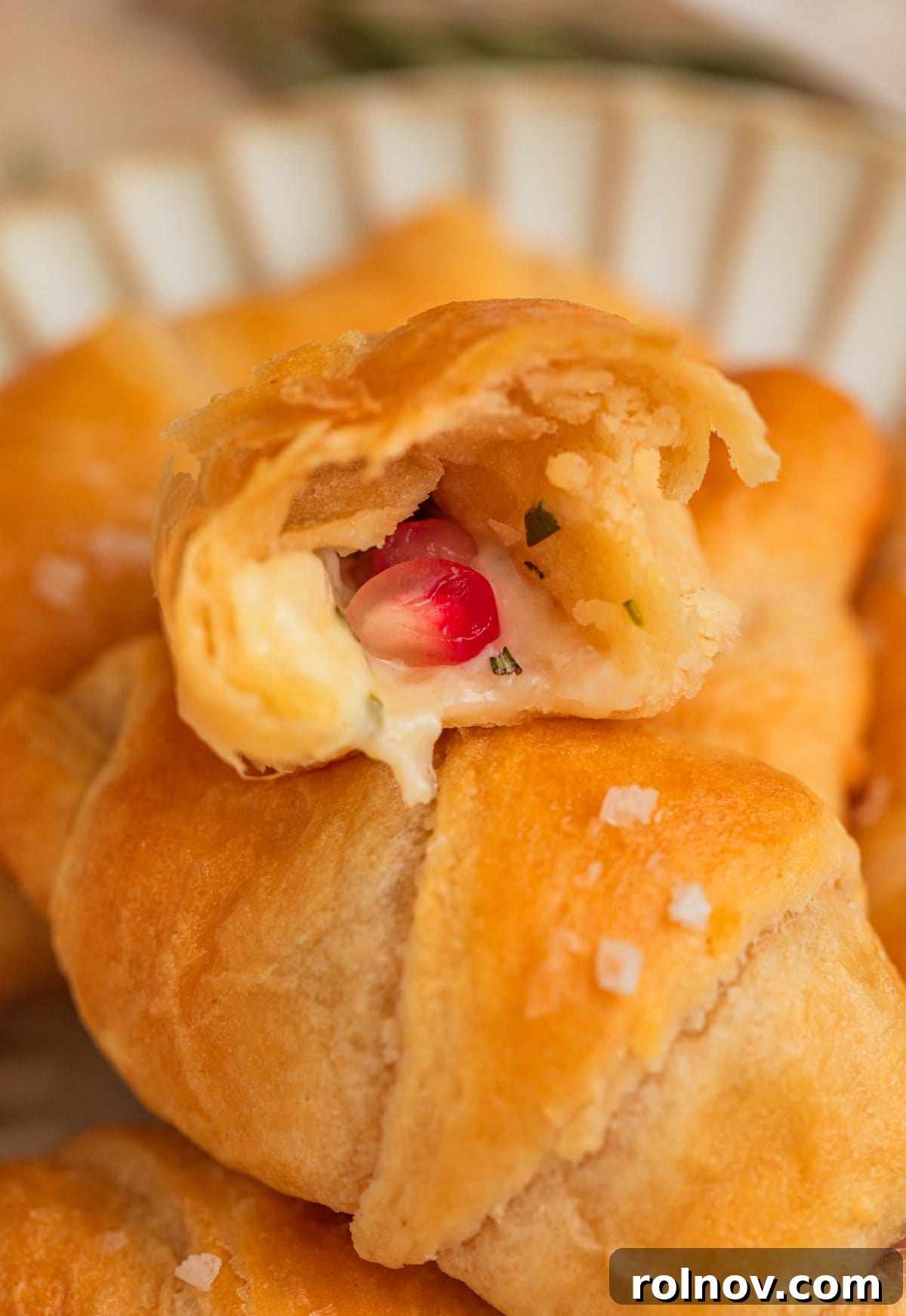Golden Flaky Brie Bites 9 A halved crescent roll revealing the melted brie cheese and pomegranate arils inside.