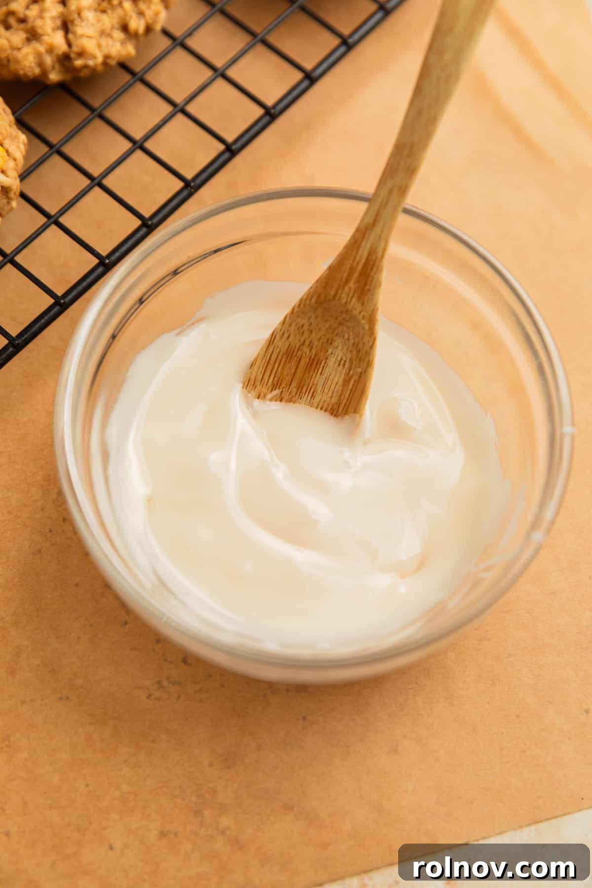 Morning Cinnamon Swirl Cookies 11 Smooth white icing glaze in a bowl with a wooden spoon, ready for drizzling.