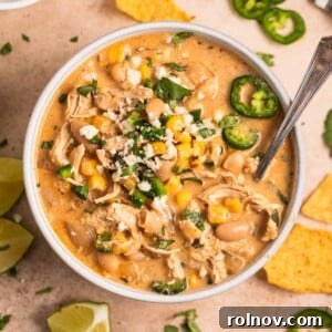 White bowl with white chicken chili with toppings and spoon.