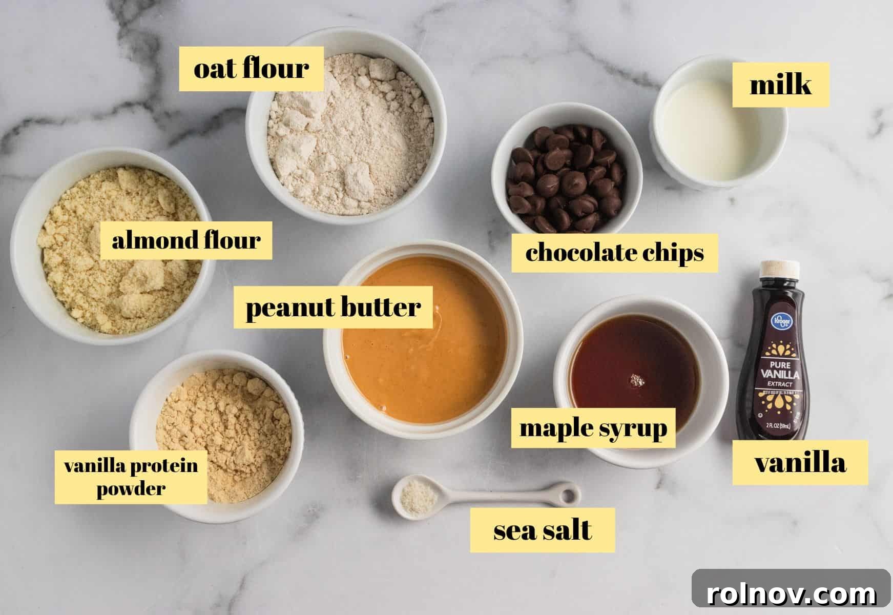 A collection of ingredients laid out, including peanut butter, flours, protein powder, and chocolate chips, ready to make homemade protein bars.