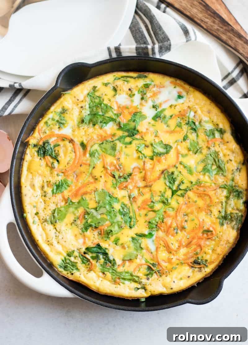 Sweet Potato Arugula Spiral Frittata 3 Sweet potato frittata baked to golden perfection in a rustic cast iron skillet, showcasing its vibrant ingredients.
