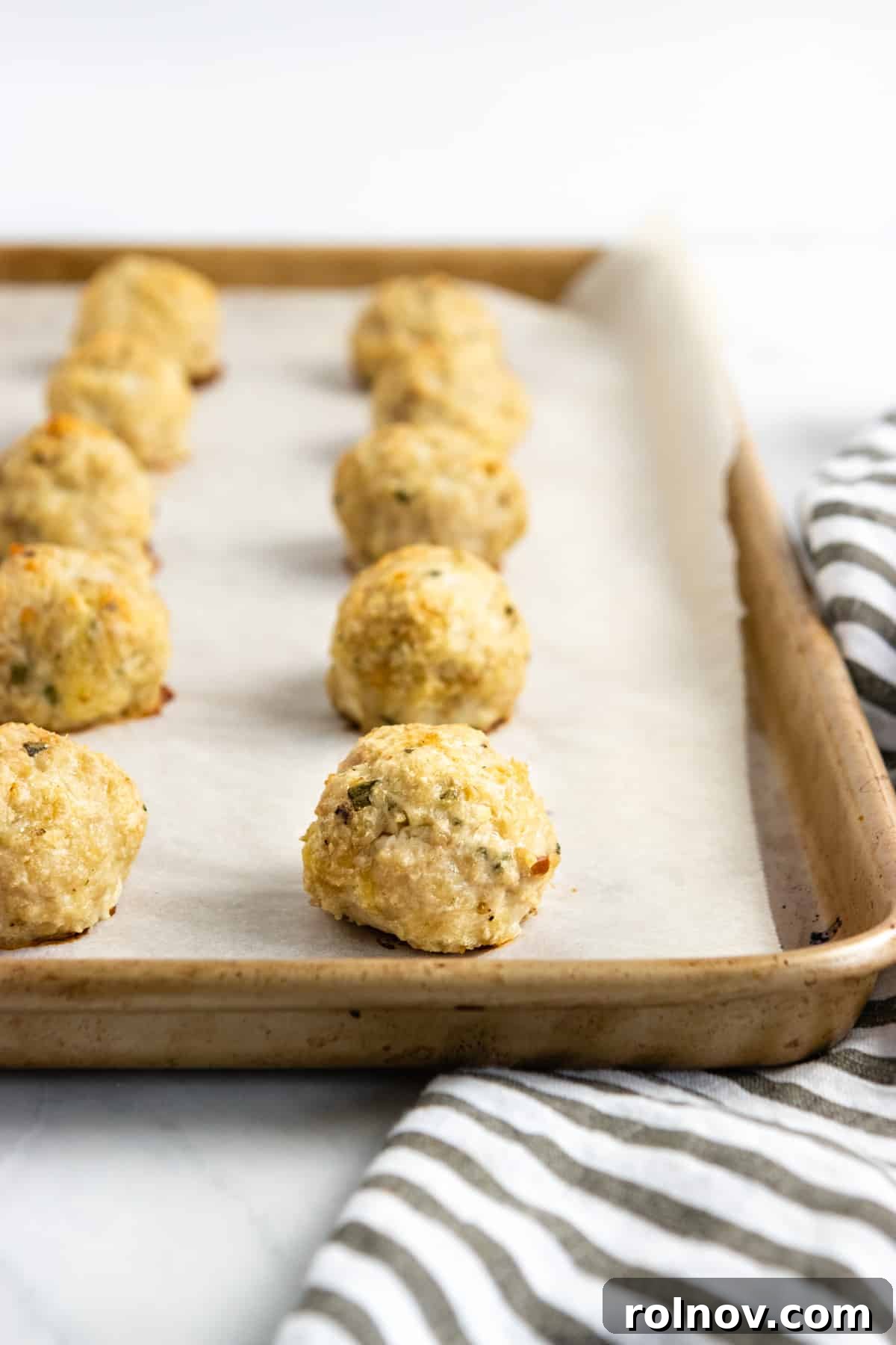 Oven-Baked Rosemary Parmesan Chicken Meatballs 2 Flavorful chicken meatballs cooked to golden perfection on a sheet pan, ready to be served.