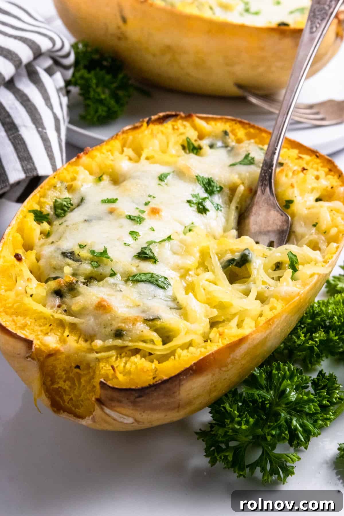Luxe Pesto Spaghetti Squash Strands 2 Delicious spaghetti squash with a creamy pesto and cheese topping, ready to be served with a spoon.