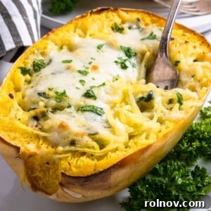 Creamy pesto spaghetti squash half with a fork.