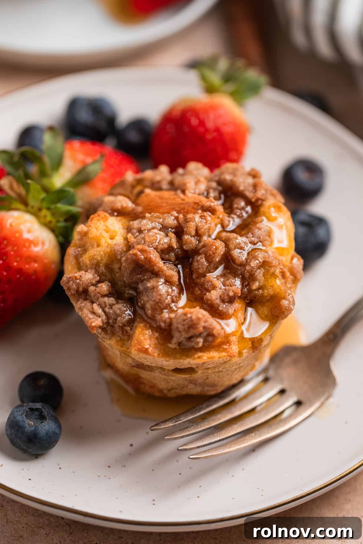 Golden French Toast Bites 2 Baked French toast muffin with streusel topping and maple syrup over top.