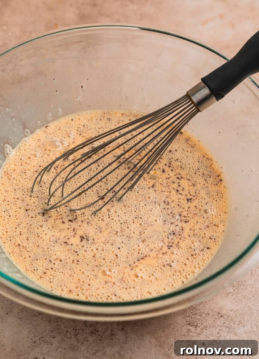 Golden French Toast Bites 6 French toast egg mixture in glass bowl with whisk.