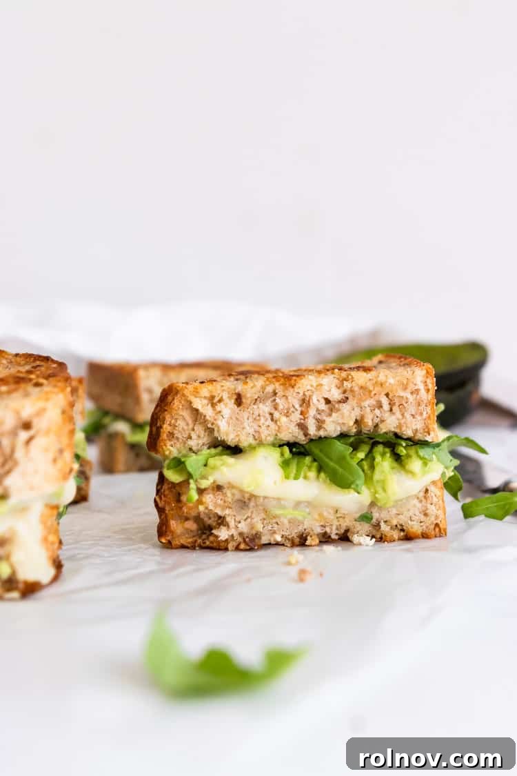 Decadent Havarti Grilled Cheese with Creamy Avocado and Peppery Arugula 4 Close-up of a halved Havarti grilled cheese, showcasing the melted cheese, creamy avocado spread, and fresh arugula.