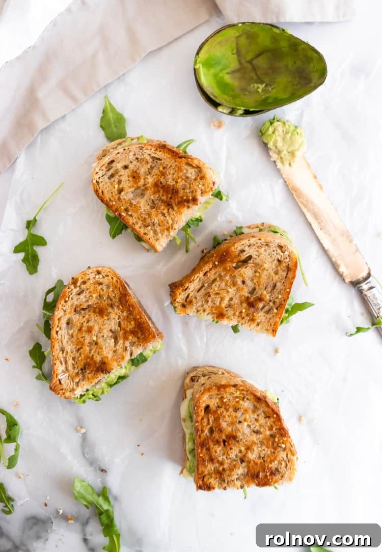 Decadent Havarti Grilled Cheese with Creamy Avocado and Peppery Arugula 6 A plate featuring a golden-brown Havarti grilled cheese with a side of soup, creating a perfect comfort meal.