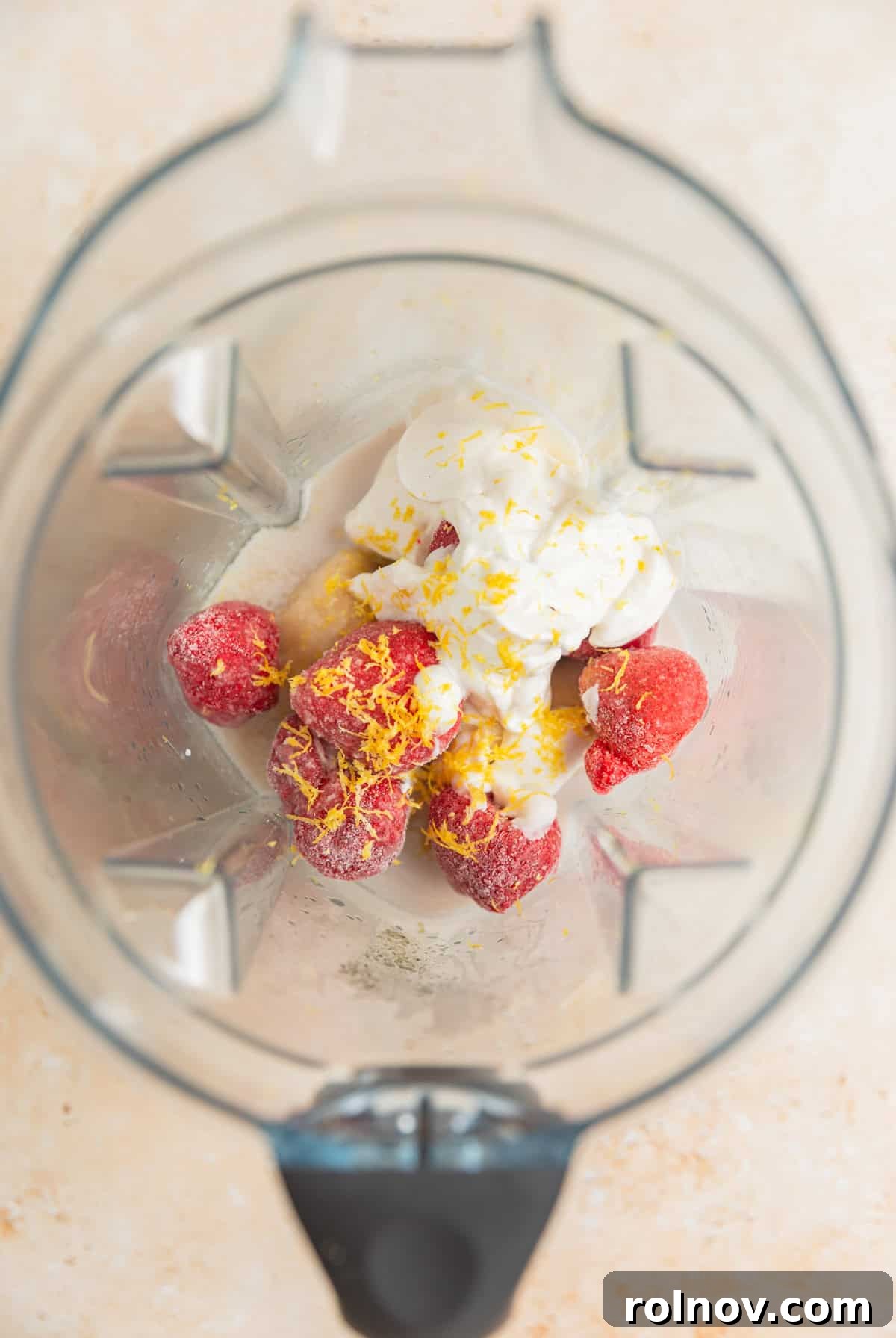 Pink Sunshine Smoothie 3 Frozen strawberries, lemon yogurt, lemon zest, frozen banana, and milk being added to a high-powered blender.