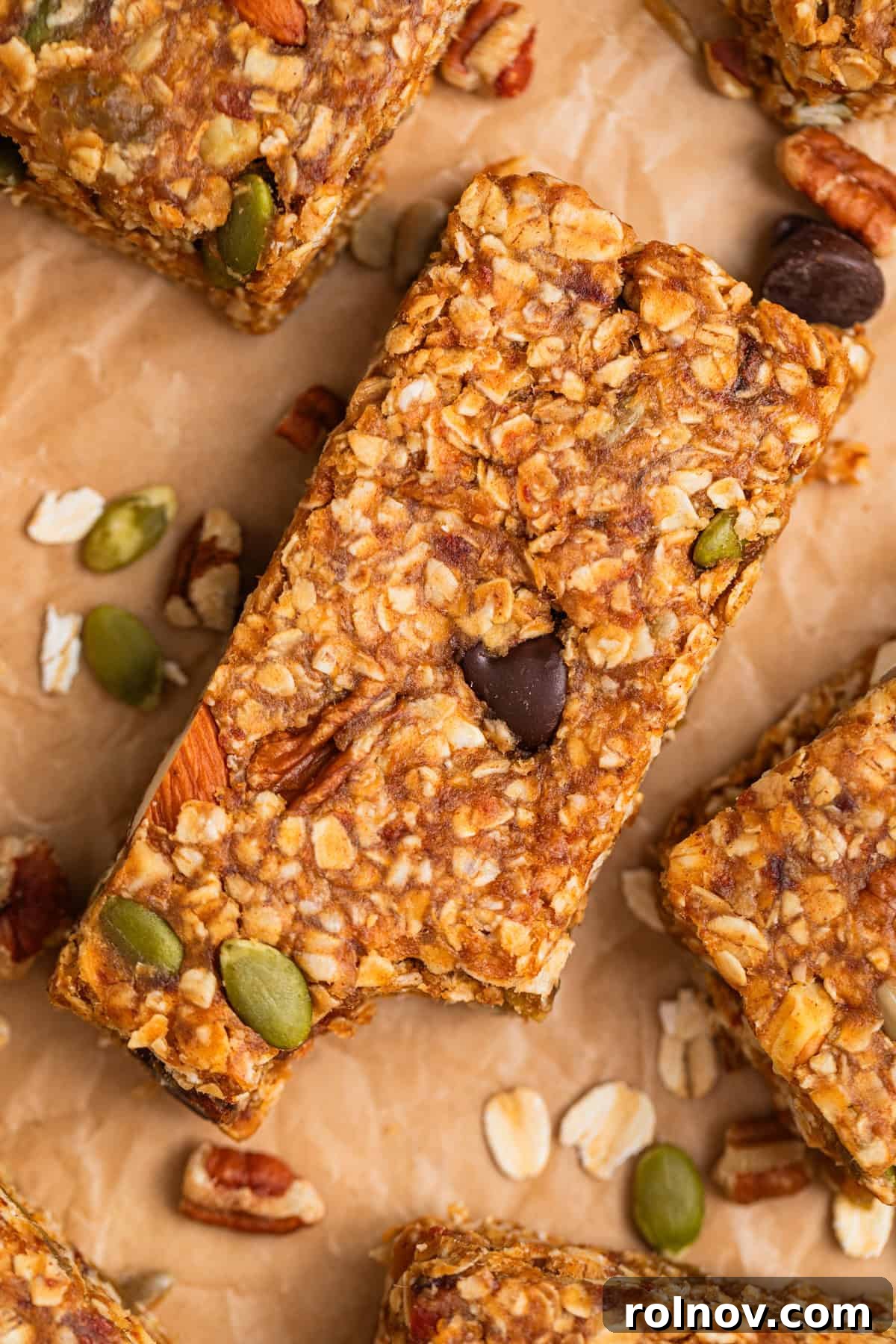 Adventure Fuel Bars 2 No bake trail mix bar on parchment with bite taken out of it, showcasing chewy texture and rich ingredients.