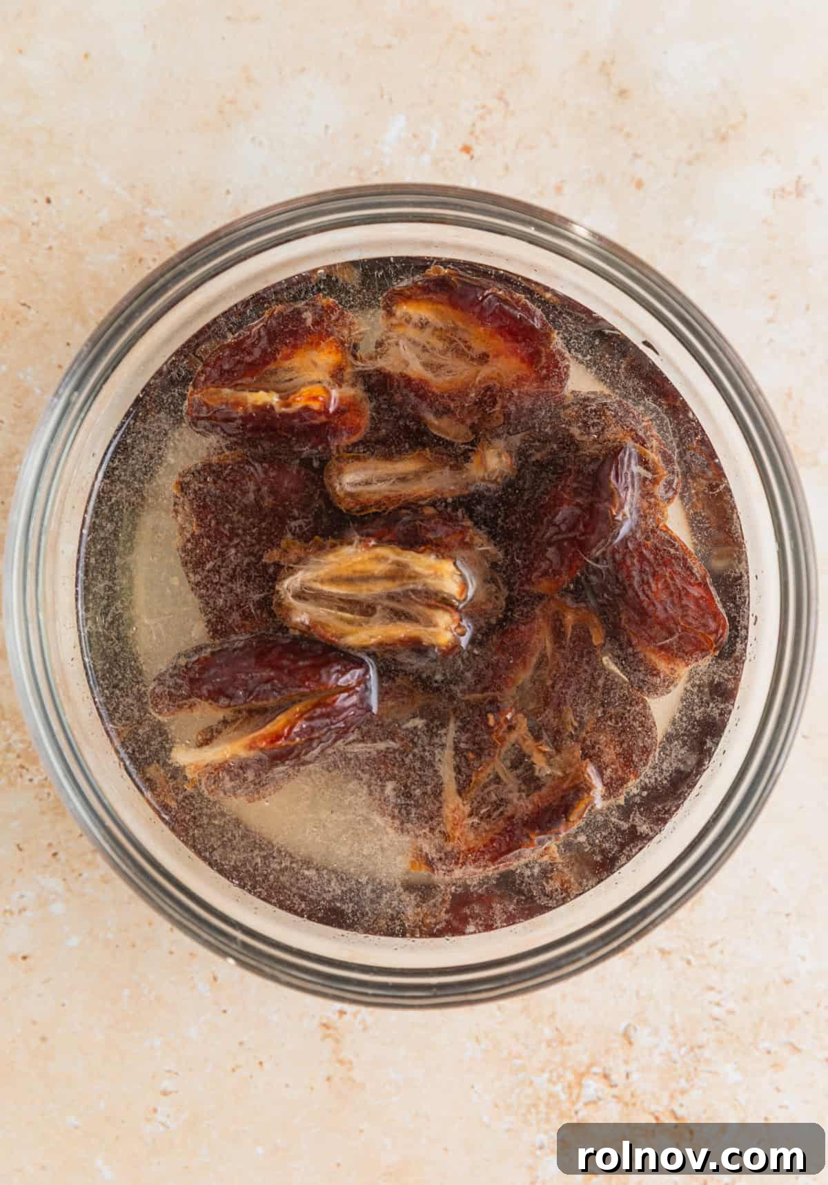 Adventure Fuel Bars 4 Medjool dates soaking in warm water in a small glass bowl, softening for processing.