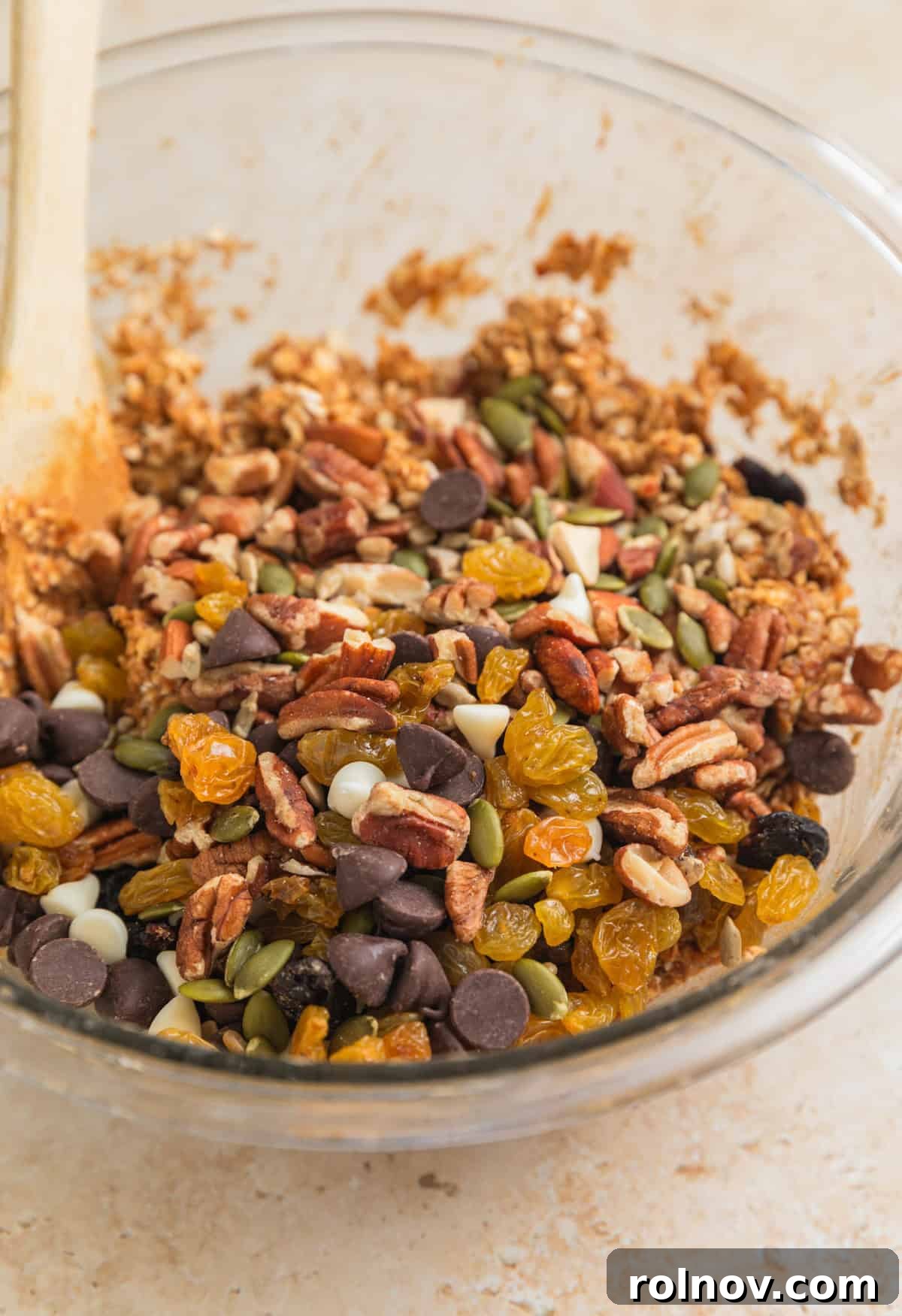 Adventure Fuel Bars 8 Assorted trail mix ingredients being added on top of the peanut butter oatmeal mixture in a bowl.