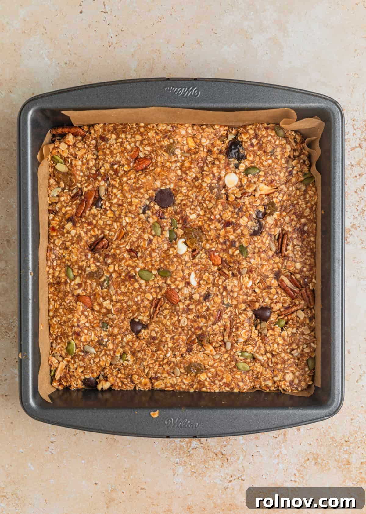 Adventure Fuel Bars 10 The trail mix oatmeal bar mixture firmly pressed into a parchment-lined 8x8 inch baking pan.