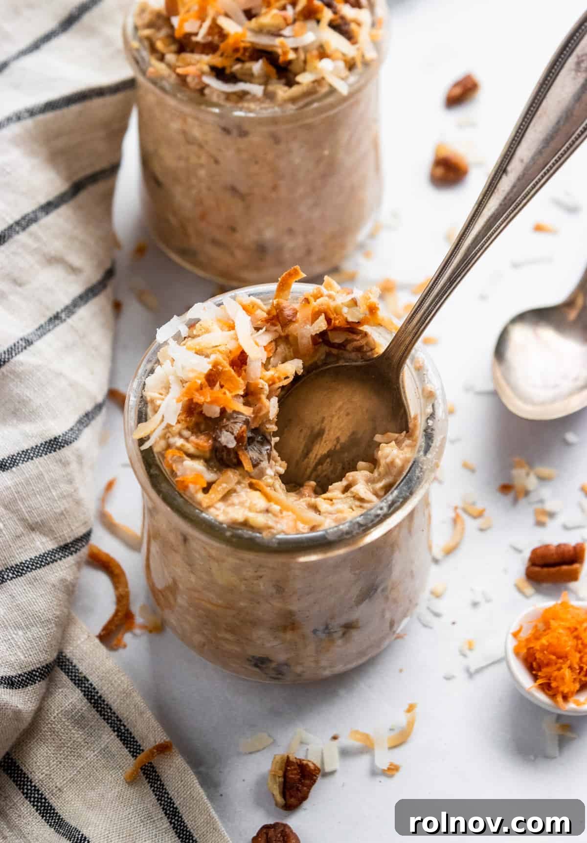 Spiced Carrot Cake Overnight Oats 6 A glass jar of Carrot Cake Overnight Oats with a spoon scooping out a portion, highlighting the texture and mix-ins.