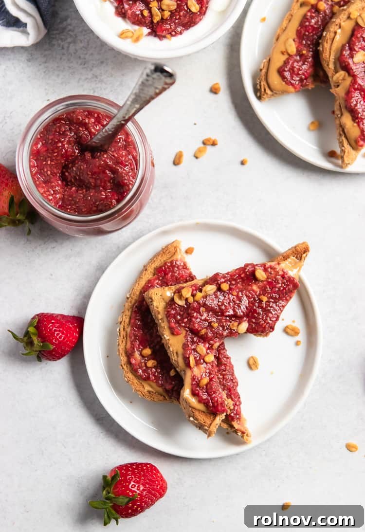 Overhead view of a slice of peanut butter toast with strawberry chia jam, showing a bite taken out.