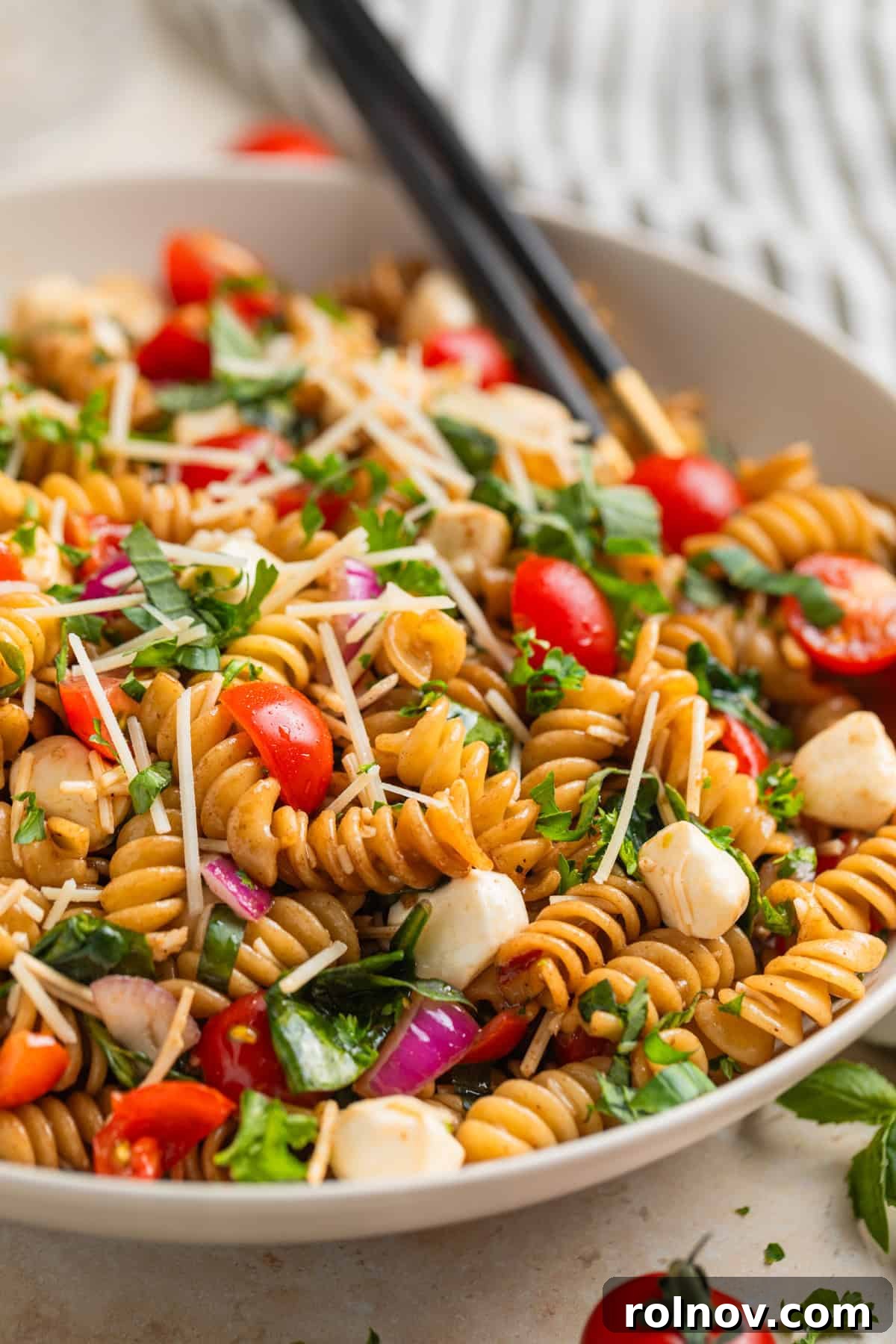 Sun-Kissed Tomato Basil Pasta Salad 2 Tomato basil pasta salad with fresh mozzarella topped with chopped parsley in serving dish.