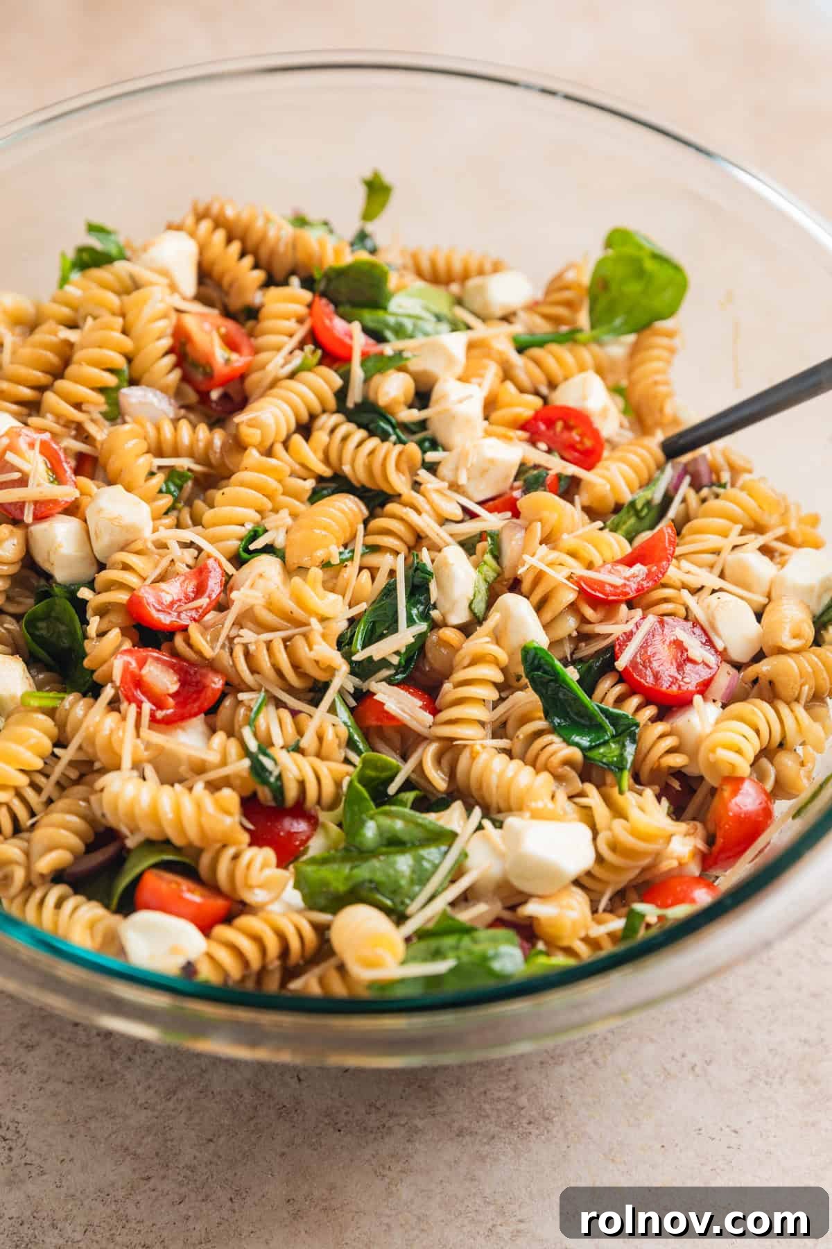 Sun-Kissed Tomato Basil Pasta Salad 8 Pasta salad mixture tossed with dressing in bowl with spoon.