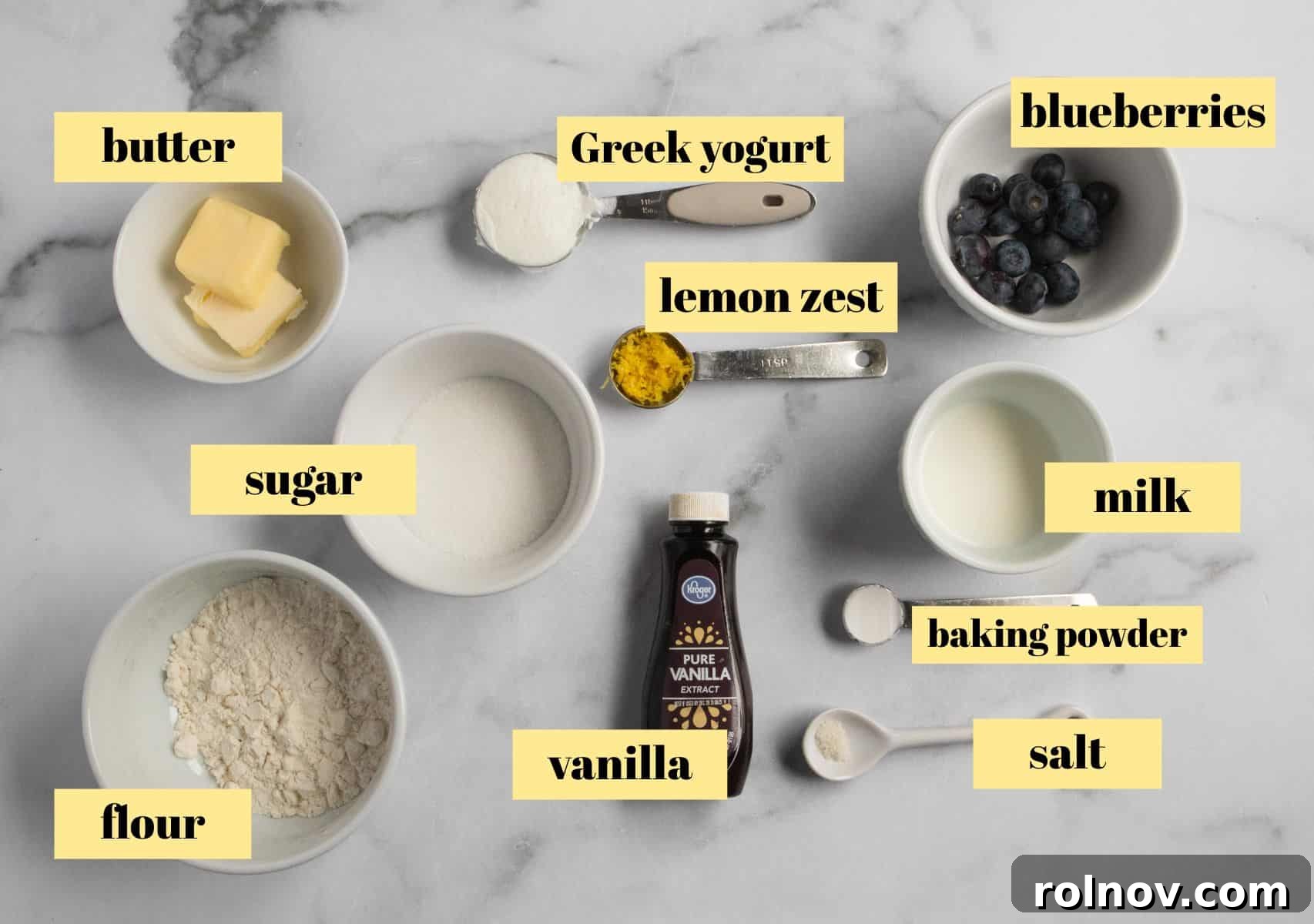 Sunny Blueberry Lemon Mug Cake 3 A collection of fresh ingredients laid out on a kitchen counter, including blueberries, lemons, milk, and yogurt, ready for baking.