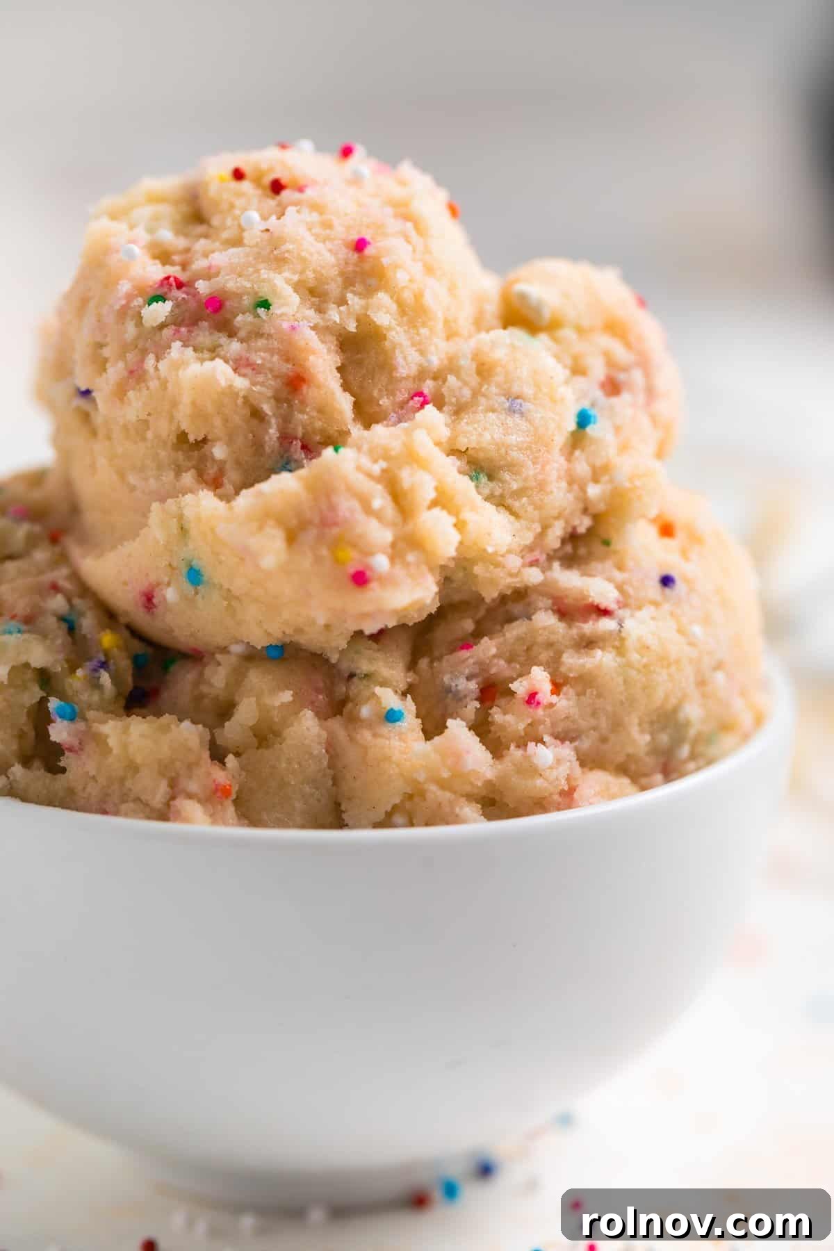 Spoonable Sugar Cookie Dough 2 A scoop of vibrant funfetti edible sugar cookie dough in a white bowl, ready to be enjoyed.