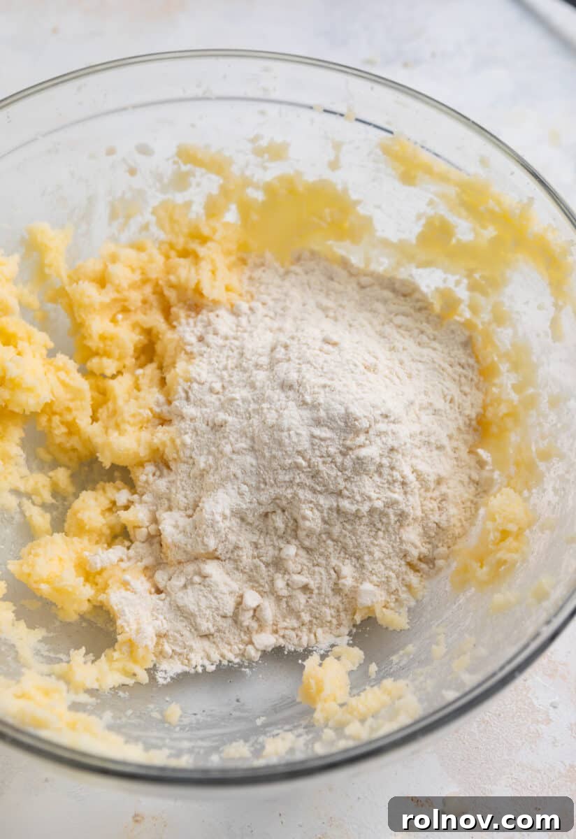 Spoonable Sugar Cookie Dough 4 Heat-treated flour being slowly incorporated into the creamed butter and sugar mixture in a mixing bowl.