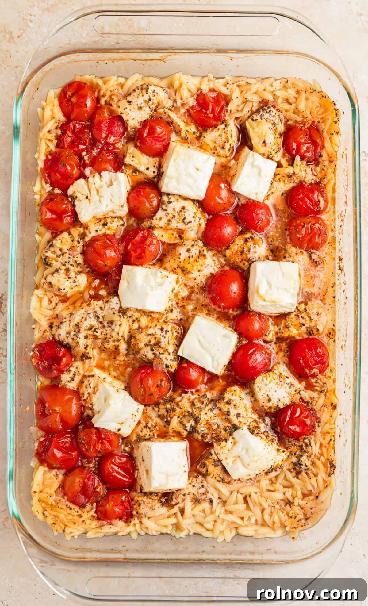 Aegean Chicken and Orzo Bake 7 A baking pan, fresh out of the oven, showing the baked Greek chicken and orzo with perfectly cooked pasta, tender chicken, and softly melted feta, steam gently rising, before final stirring and garnishing.