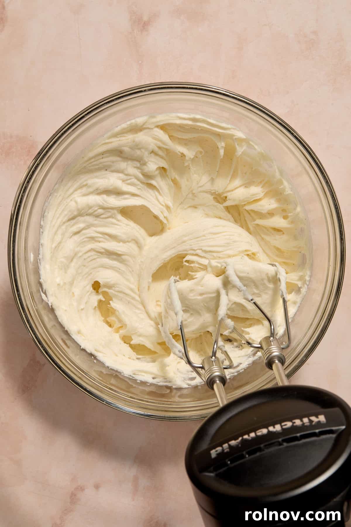 Smooth, creamy vanilla bean buttercream frosting being prepared in a bowl with an electric mixer.