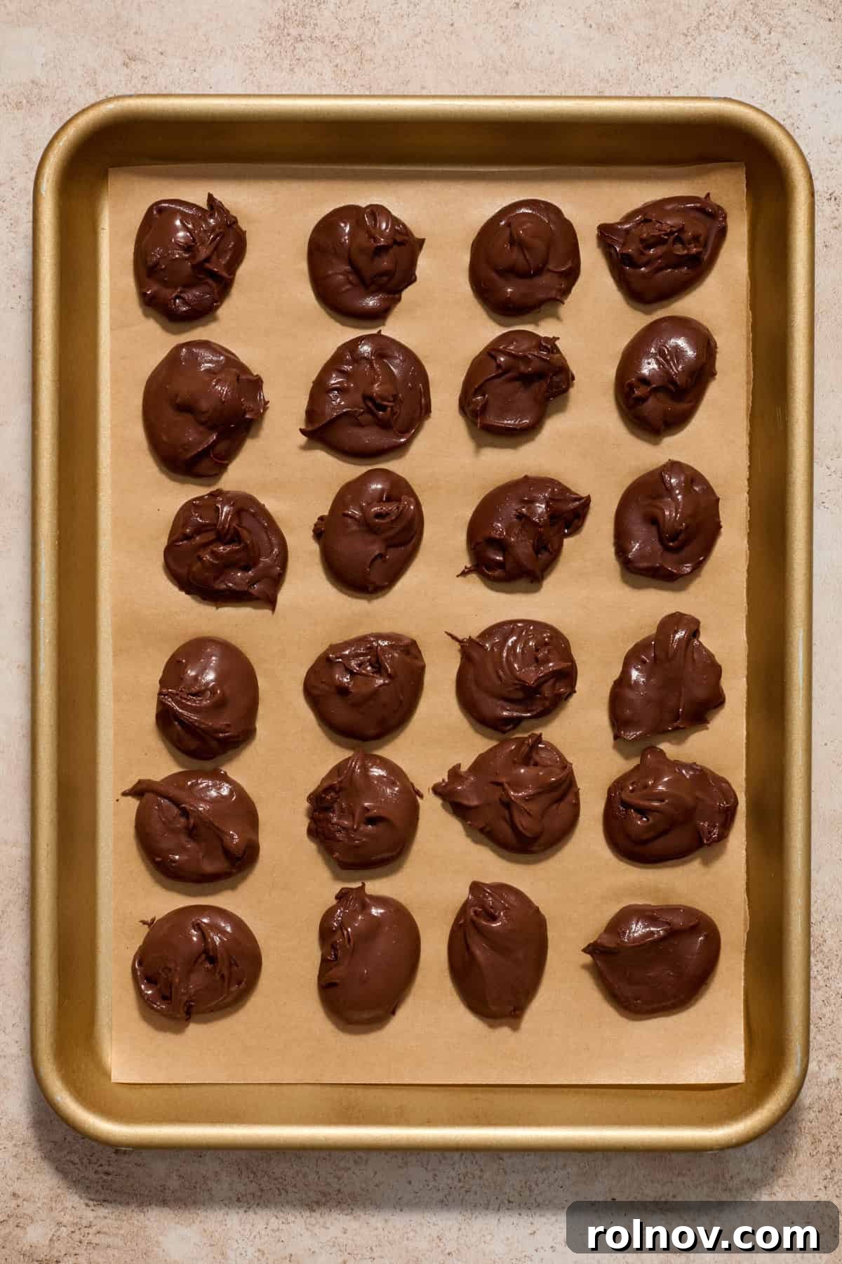 Small dollops of chocolate ganache spooned onto a parchment-lined baking pan.