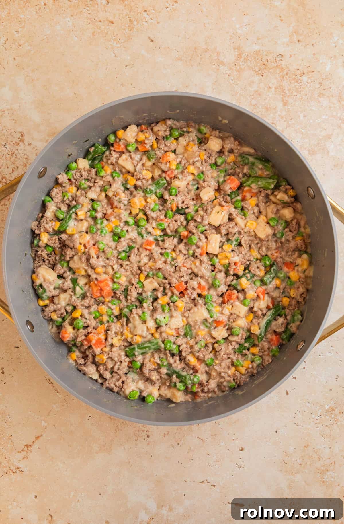 Comforting Ground Turkey Pot Pie 6 The ground turkey mixture combined with creamy soup, mixed vegetables, and peas in a pan, ready for the puff pastry.