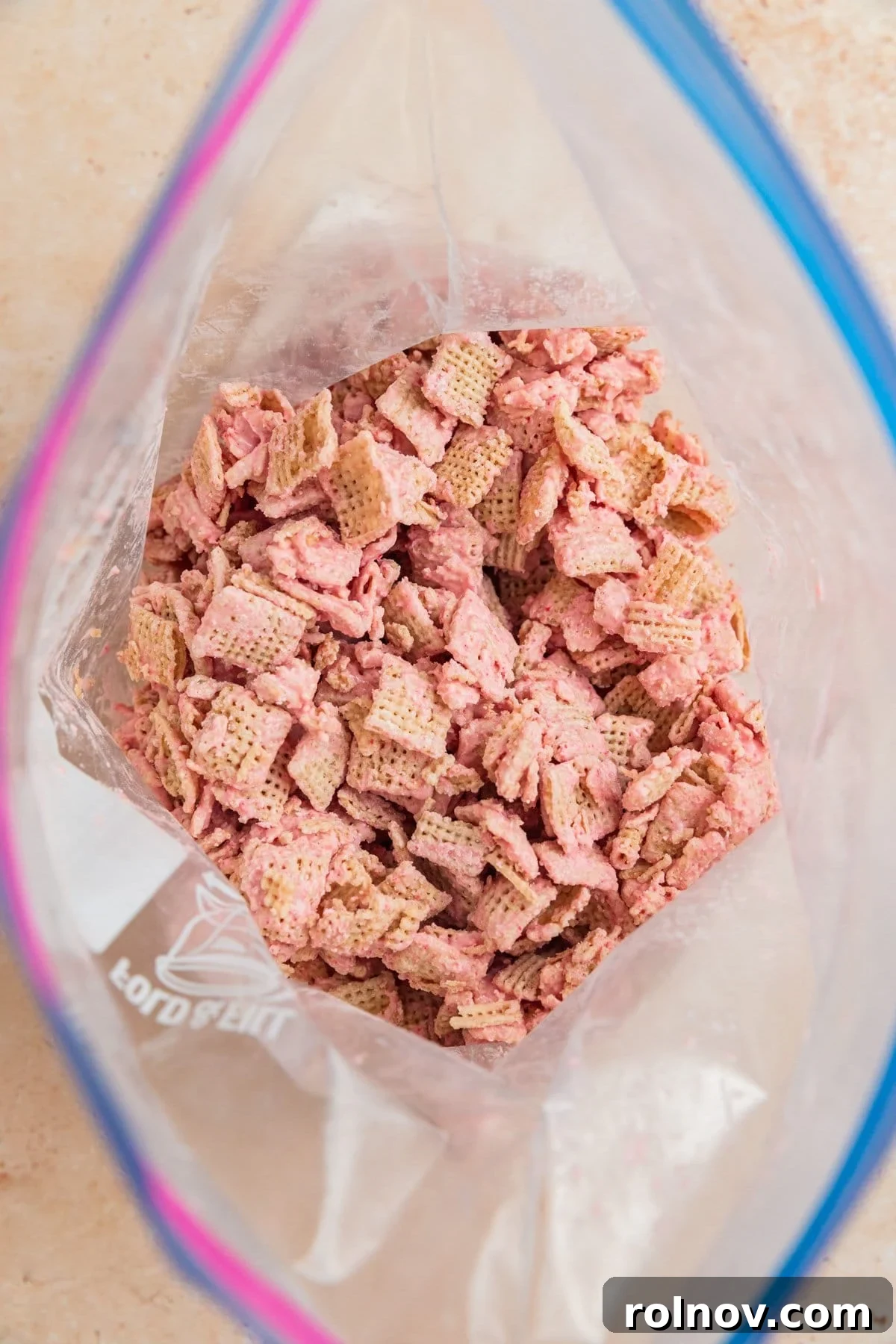Sweet Strawberry Crunch 11 The strawberry white chocolate coated Chex cereal mixture being transferred into the ziplock bag with powdered sugar.