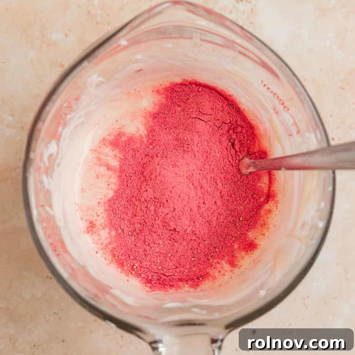 Sweet Strawberry Crunch 6 Strawberry powder being stirred into melted white chocolate in a mixing cup.