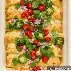 Pan of green chicken enchiladas topped with onion, cilantro, tomatoes, etc.