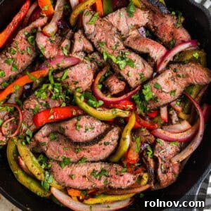 Skillet with steak fajitas topped with cilantro.