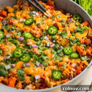 Ground turkey sweet potato skillet dinner in pan with spoons scooping into the skillet.