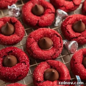 Red velvet cookies with Hershey kiss centers on wire rack.