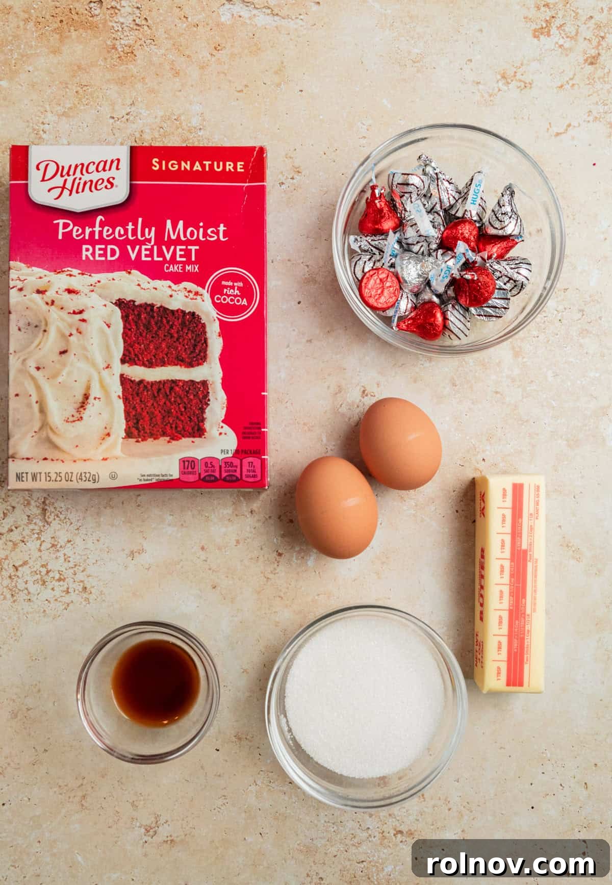 Red velvet cake mix box, Hershey's Kisses, eggs, butter, and other baking ingredients laid out.